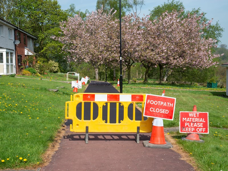 Barriers and signs in front of resurfaced pavement