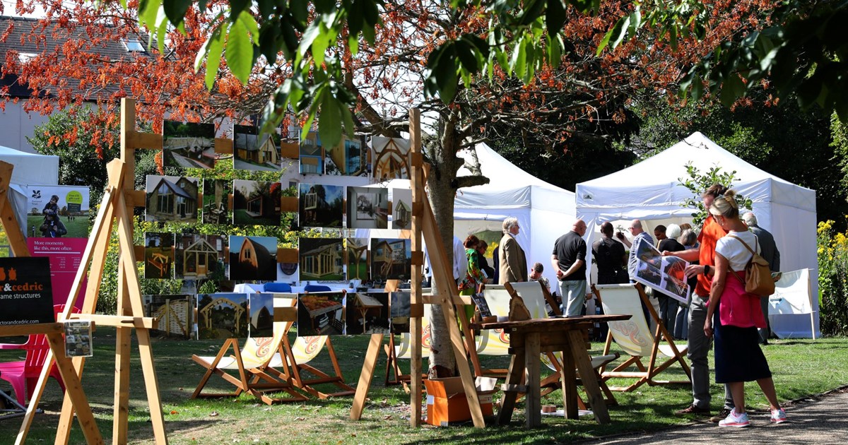 Visitors enjoying the different artwork displayed at Art in the Gardens, among a scenic background of trees