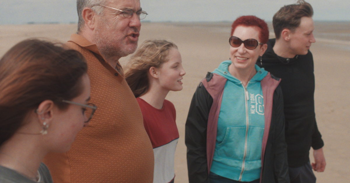 Two adults and 3 young people on a windy beach