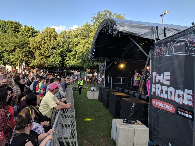 crowd of people looking up at a stage with trees in the background